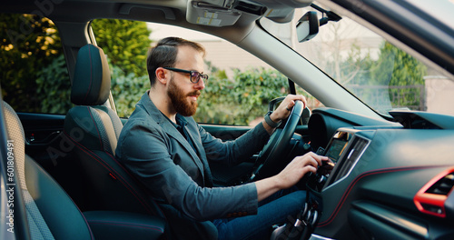 Side view of caucasian businessman making scrolling and typing text on touch screen monitor on car. © serg