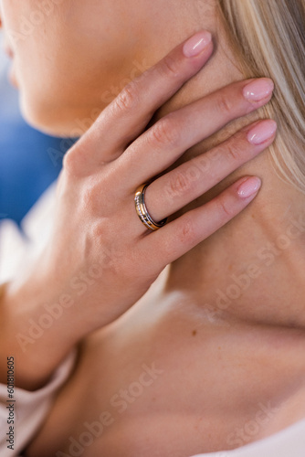Pretty beautiful blonde girl holds her hand to neck, showing off a gorgeous wedding ring in a jewelry store. The model has a slender and delicate neck. Jewelry advertising.