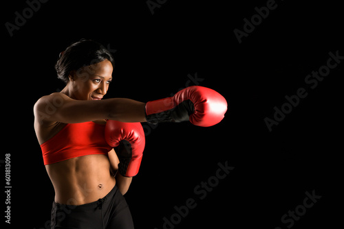 African American young adult woman wearing boxing gloves throwing punch. © Designpics