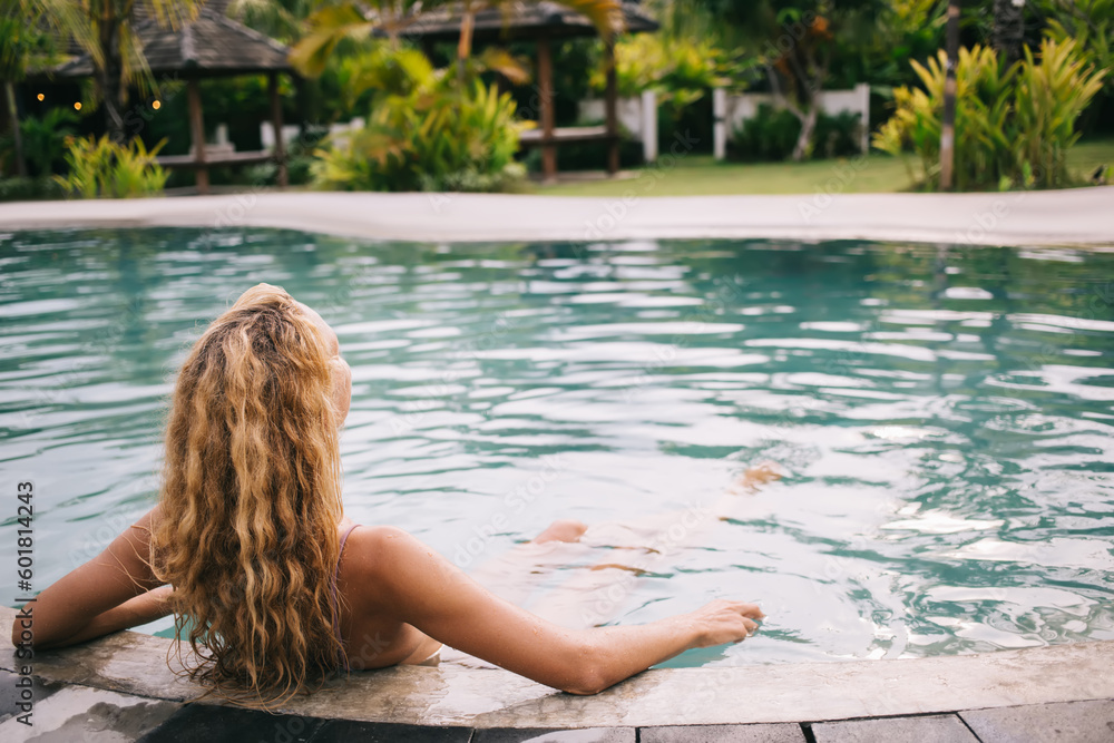 Unrecognizable young woman resting in water on poolside