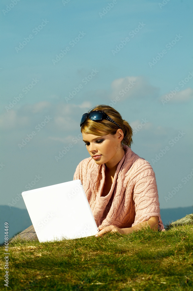 Young business woman relaxing, working on laptop computer on meadow