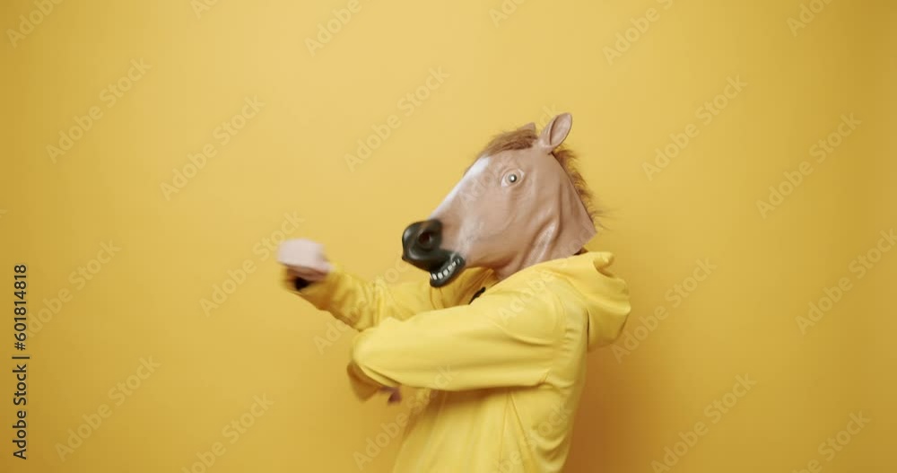 Man with horse mask making funny gestures. Funny Guy in Yellow Suits