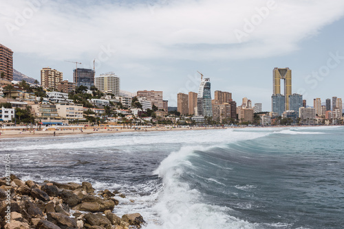 Benidorm city coastline, Alicante, Spain, view from the west beach between rocks and a nice wave. At the back the beach with people and some emblematic buildings. © Beti Argi