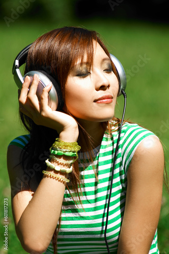 Beautiful asian young girl with headphones, listen to music on meadow