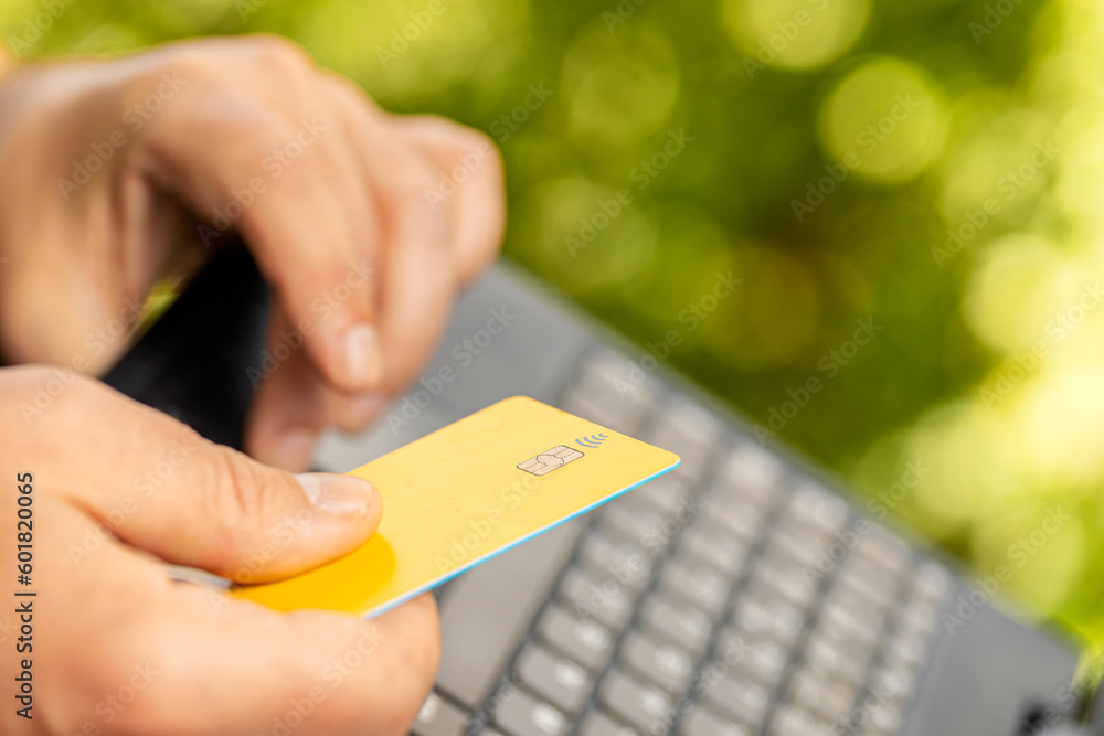 online payments by credit card. Man with credit card in hand and a laptop making online purchases and payments on the Internet, Selective focus and natural blur background. Chip bank card concept online payments by credit card. Man with credit card in hand and a laptop making online purchases and payments on the Internet, Selective focus and natural blur background. Chip bank card concept