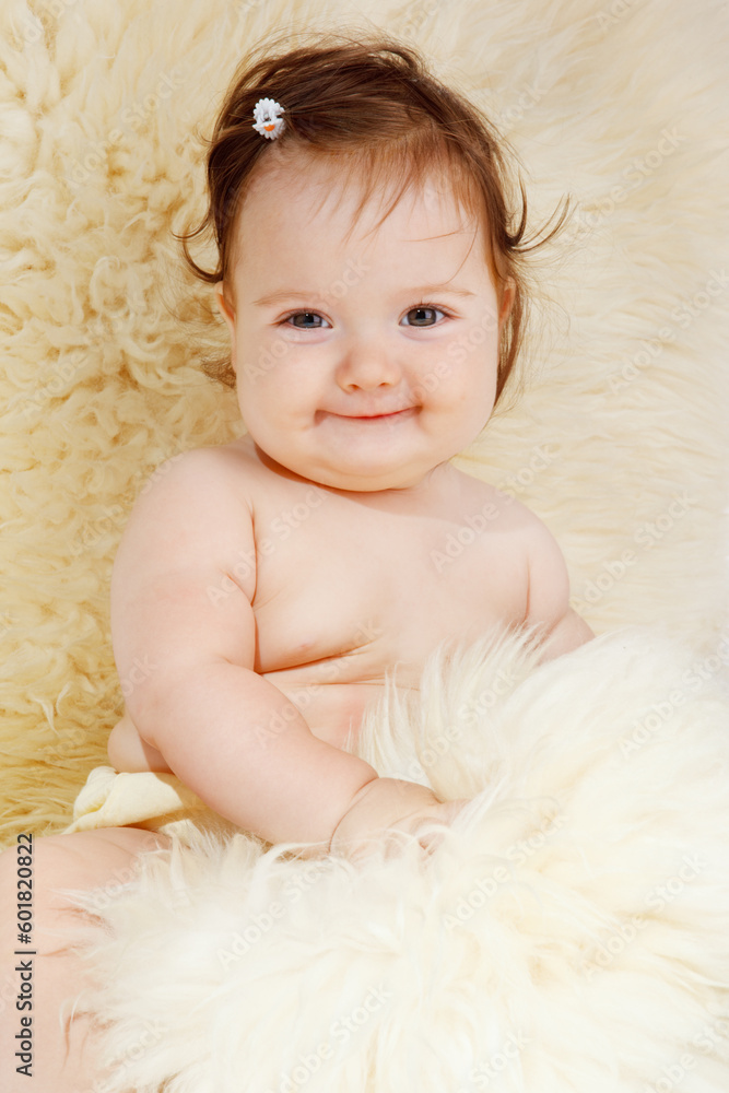 Beautiful baby girl sitting covered with sheepskin Beautiful baby girl sitting covered with sheepskin