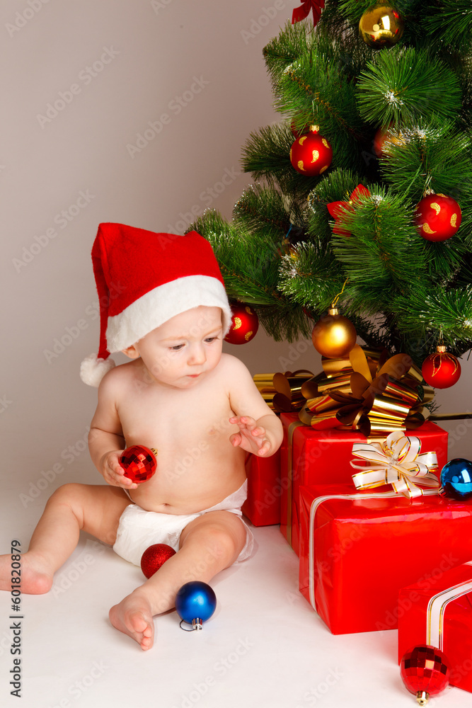 Baby boy in santa hat sitting beside presents