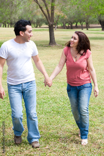 Couple walking holding hands and smiling at the park