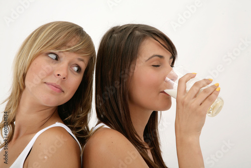 close-up of two girls over white background, one drinking milk
