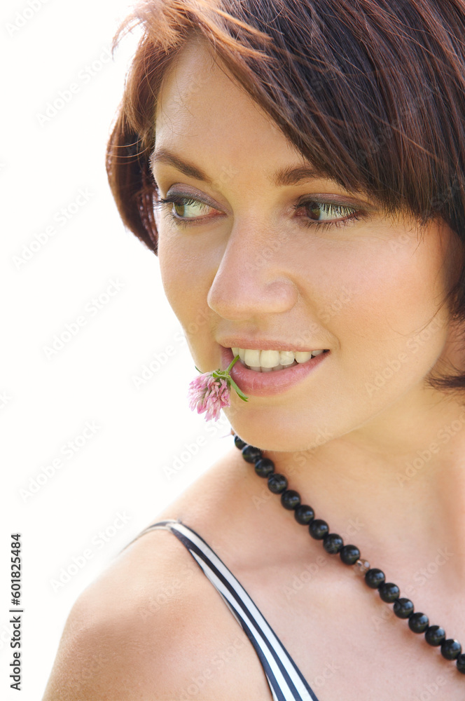 Young beautiful woman with a clover flower in a teeth