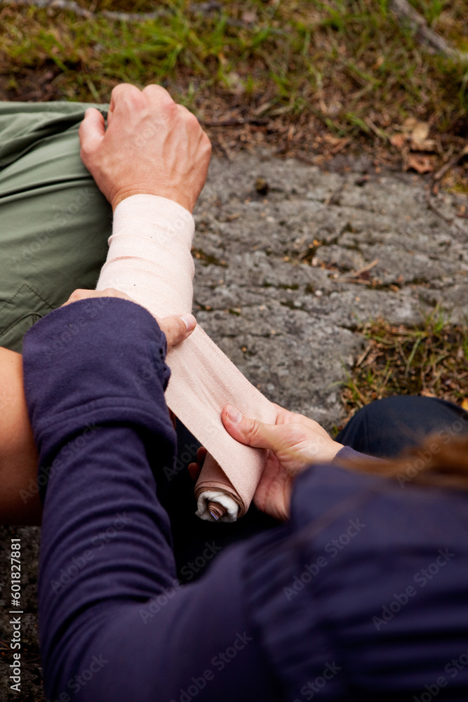 A woman applying an arm bandage on a male camper - focus on male face A woman applying an arm bandage on a male camper - focus on male face
