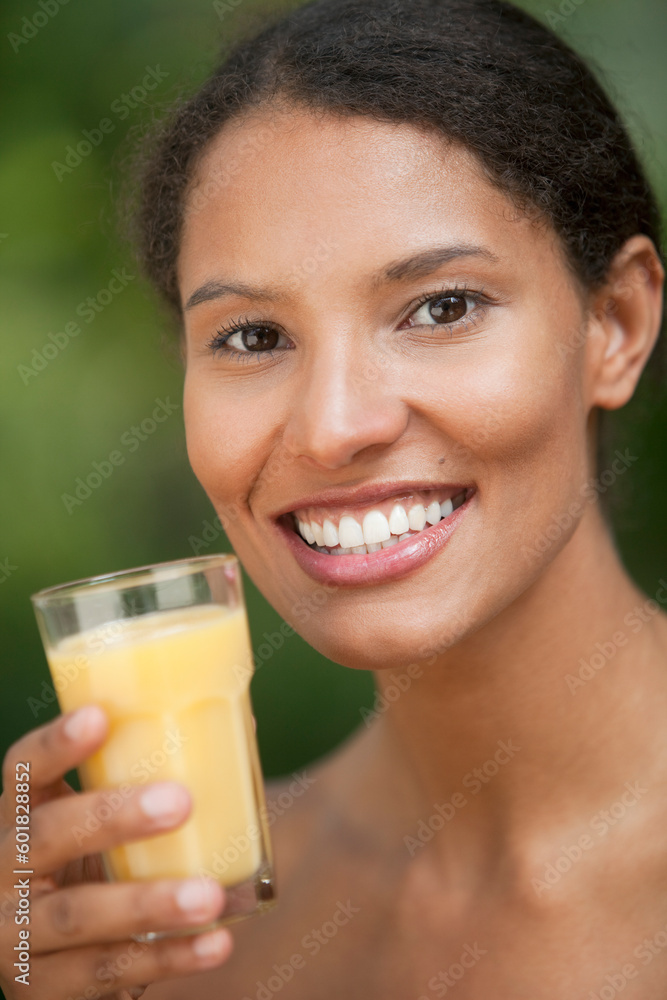 Closeup of young woman drinking orange juice in outdoor setting. Vertically framed shot. Closeup of young woman drinking orange juice in outdoor setting. Vertically framed shot.