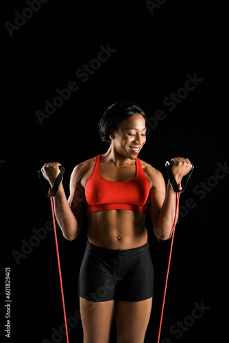 Smiling African American young adult woman exercising with resistance tube.