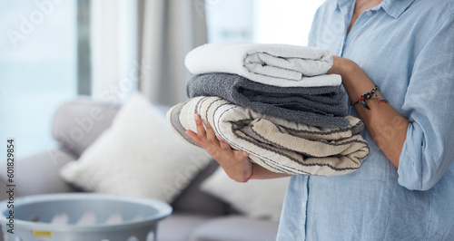 Obraz na płótnie Hands, laundry and spring cleaning with a woman holding a pile of fresh towels in the living room of her home