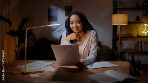 Happy young African student with positive emotions, reading article at home. People Career Education photo