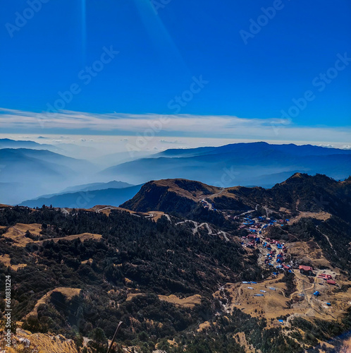 View of the beautiful Kuri village of Kalinchowk, Nepal from the top of a mountain with the clouds and mountains in the distant.
