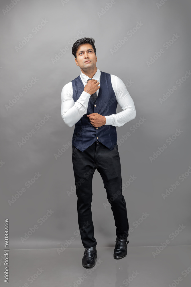 Studio shot of cheerful, young, handsome Indian business man in formal wear against grey background. Male model. Fashion Portrait. Studio shot of cheerful, young, handsome Indian business man in formal wear against grey background. Male model. Fashion Portrait.