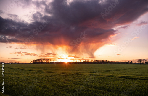 colourful sunset over wide field - heavy cloud in golden hour 