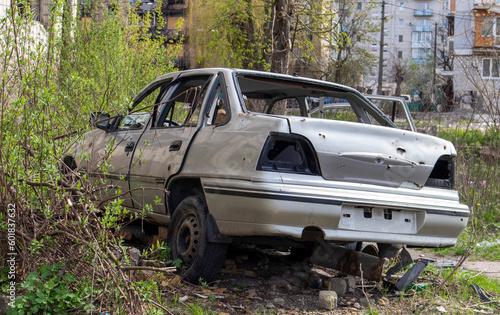 A broken Ukrainian civilian car, shot by artillery, stands in the courtyard of a destroyed house. War between Russia and Ukraine. The wreckage of an abandoned car.
