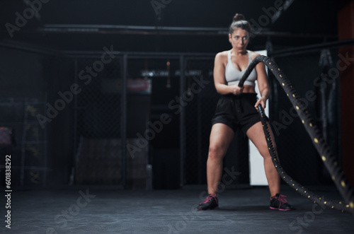 Sports, battle ropes and woman at the gym doing strength, cardio and challenge exercise with space. Fitness, energy and strong female athlete doing health workout or training with equipment for power