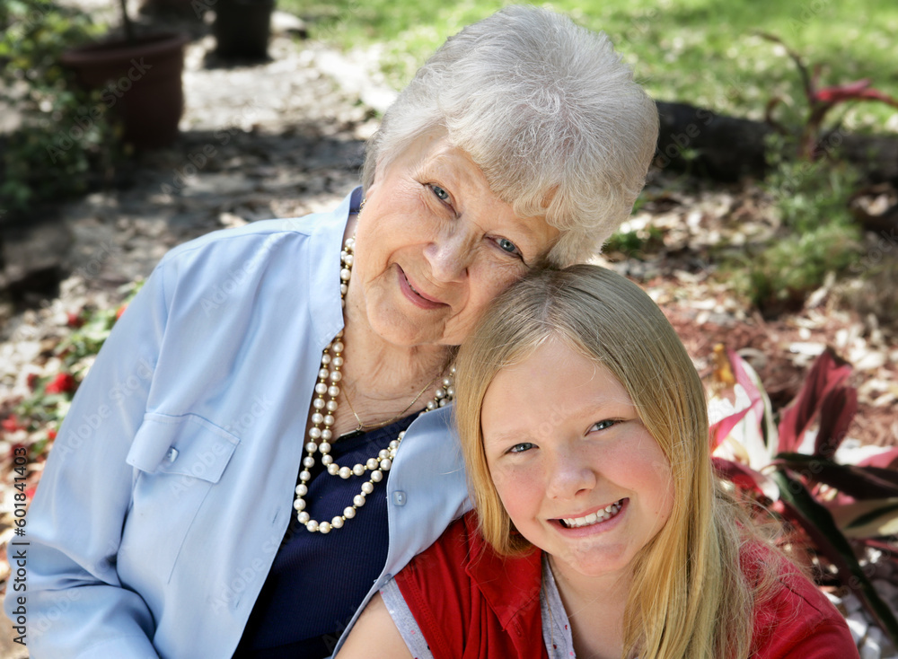 A portrait of a grandmother and granddaughter in the garden.  Horizontal composition with room for text.