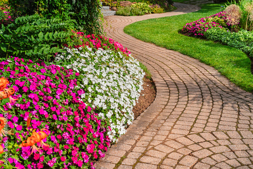 Flowerbeds of vivid colored impatiens border a winding garden path.