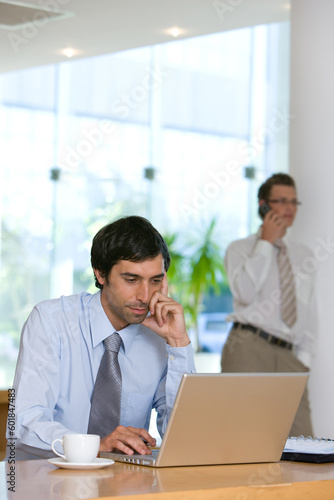 Confident young business man working on laptop