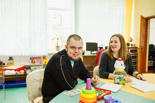an autistic adult is undergoing rehabilitation with an assistant in the classroom