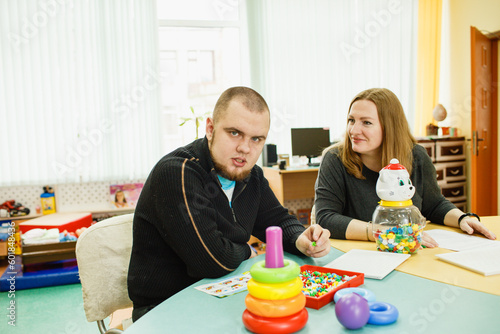 an autistic adult is undergoing rehabilitation with an assistant in the classroom photo