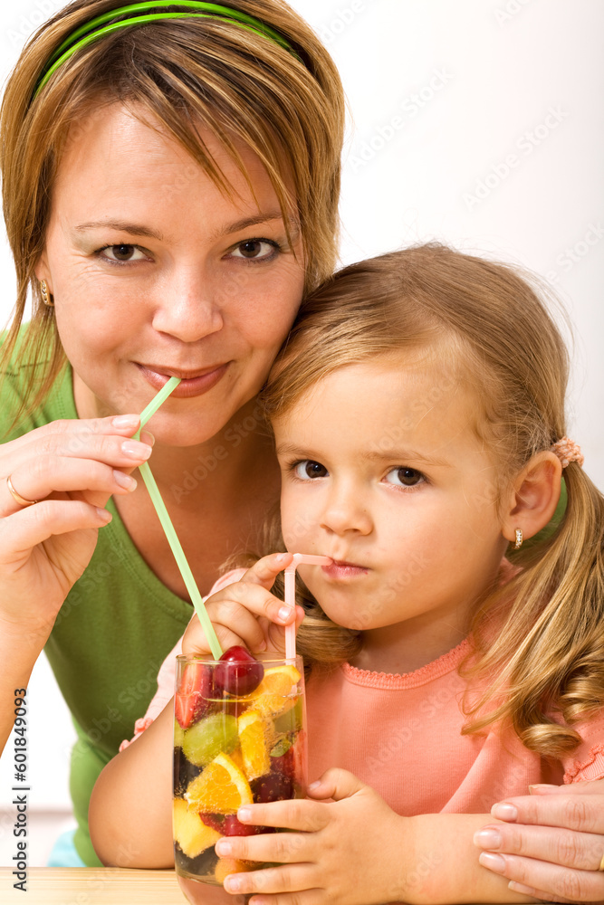 Woman and little girl sharing a fruity refreshment Woman and little girl sharing a fruity refreshment