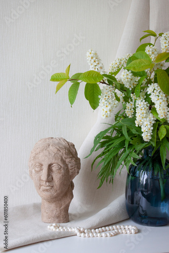 Interior decor. Flowers in a vase, clay sculpture and pearl beads in table. Selective focus