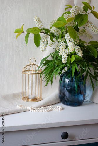 Interior decor. Flowers in a blue glass vase, a golden candlestick and pearl beads. Selective focus