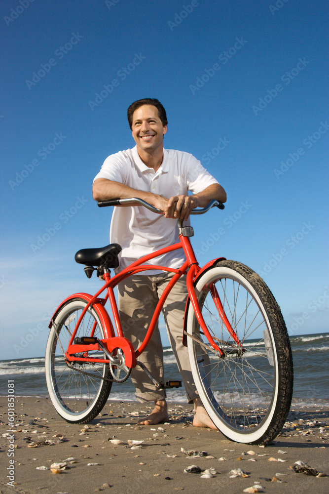 Caucasian mid-adult man posing with red bicycle on beach. Caucasian mid-adult man posing with red bicycle on beach.