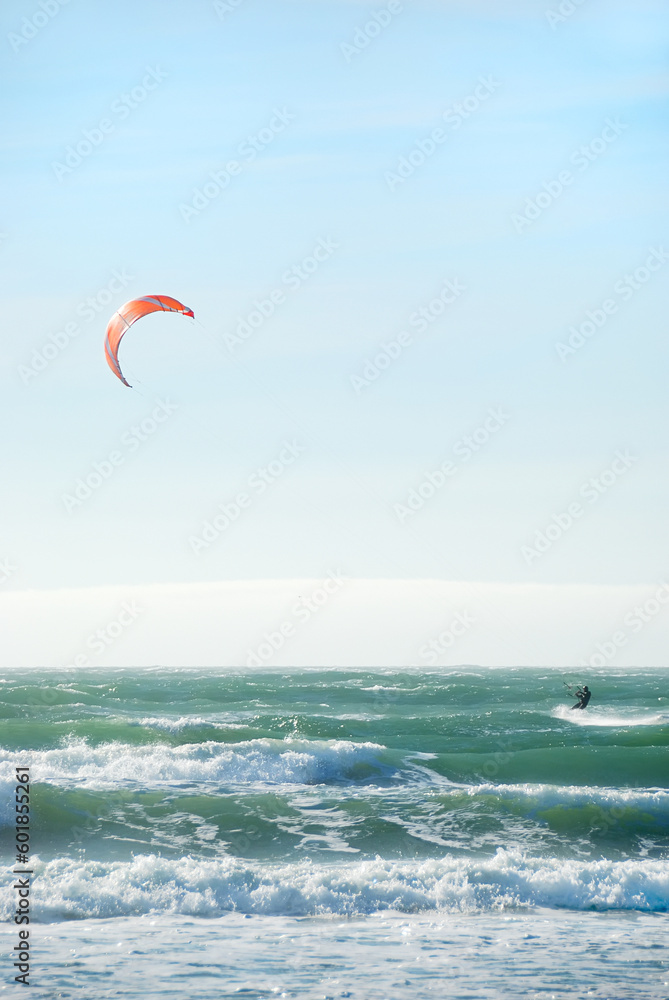 Surfer with red kite surfing off the beach in San Francisco, California on a sunny day. Surfer with red kite surfing off the beach in San Francisco, California on a sunny day.