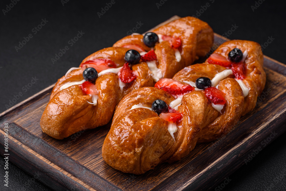 Delicious fresh crispy pastry in the form of a pigtail with strawberries and blueberries Delicious fresh crispy pastry in the form of a pigtail with strawberries and blueberries