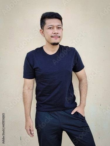 young man in black t-shirt on color background mockup for design
