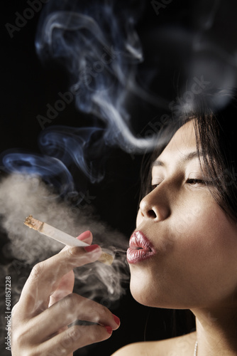 Female inhale smoke from cigarette on dark area