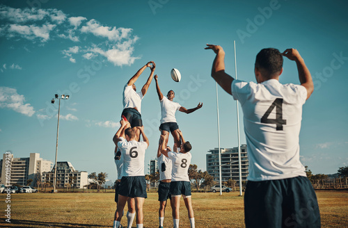 Team, rugby and jump or lift, ball and teamwork or sport, training for game and fitness, exercise or sports performance with blue sky. Group, men and lifting man to catch and professional match