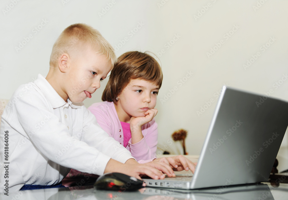 two happy children playing games and learnig education lessons on laptop computer at home two happy children playing games and learnig education lessons on laptop computer at home