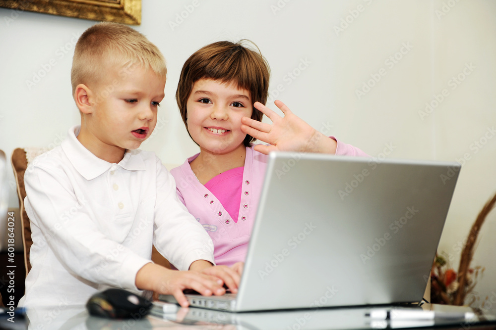 two happy children playing games and learnig education lessons on laptop computer at home two happy children playing games and learnig education lessons on laptop computer at home