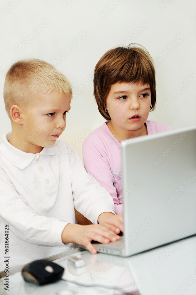 two happy children playing games and learnig education lessons on laptop computer at home two happy children playing games and learnig education lessons on laptop computer at home