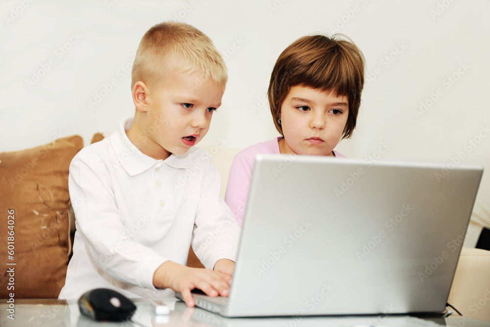 two happy children playing games and learnig education lessons on laptop computer at home two happy children playing games and learnig education lessons on laptop computer at home