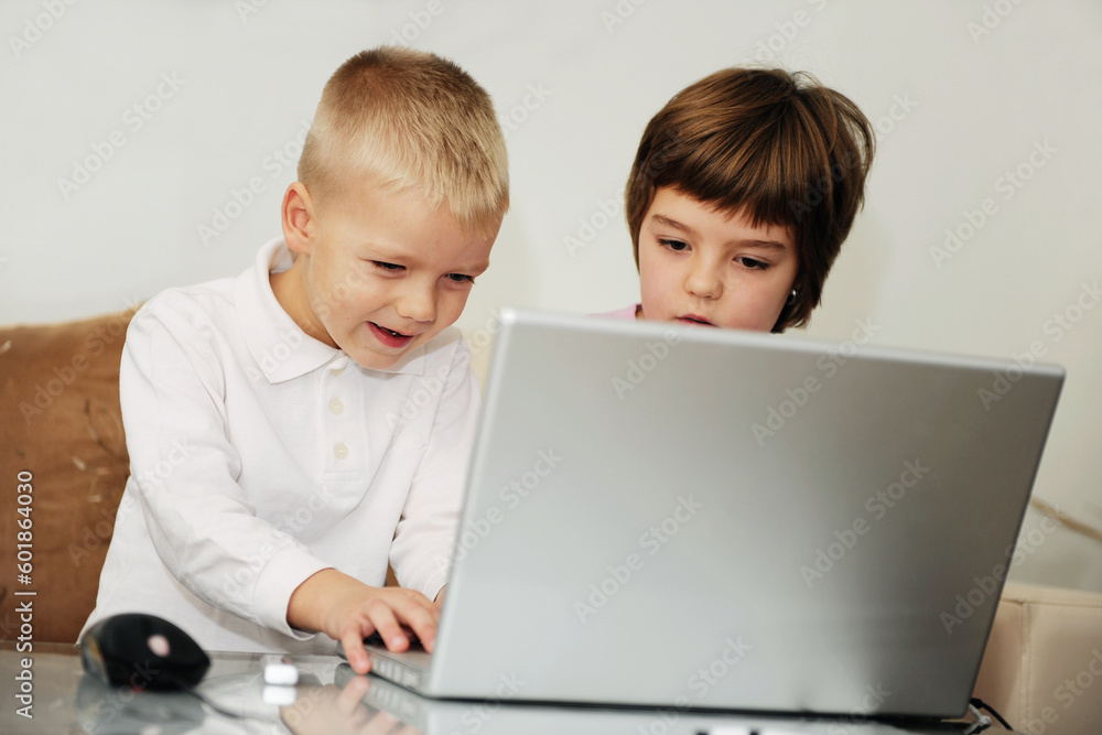 two happy children playing games and learnig education lessons on laptop computer at home two happy children playing games and learnig education lessons on laptop computer at home