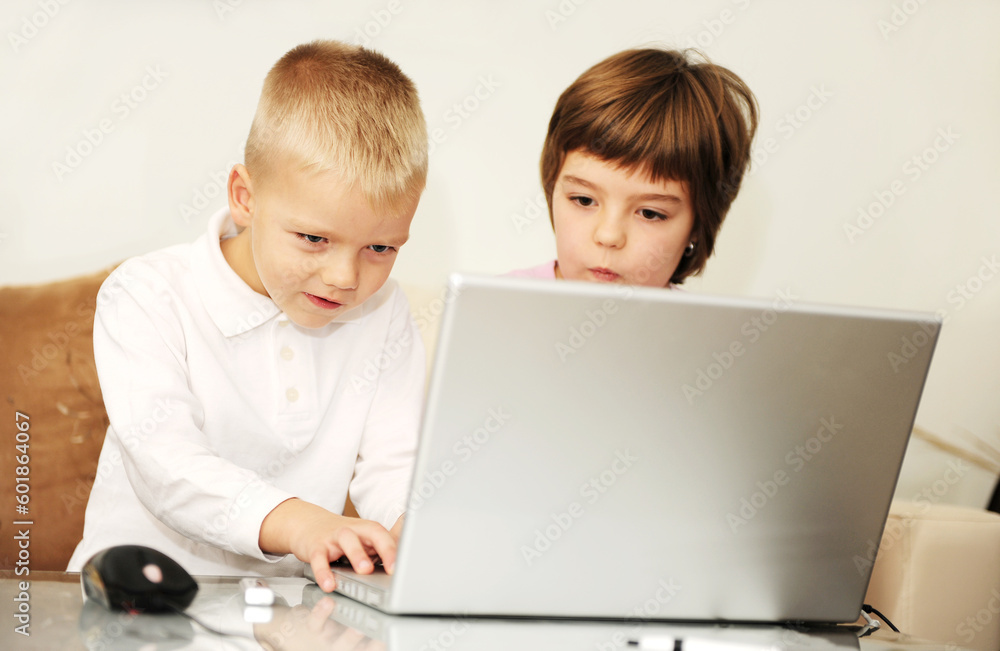 two happy children playing games and learnig education lessons on laptop computer at home two happy children playing games and learnig education lessons on laptop computer at home
