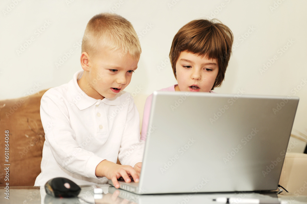 two happy children playing games and learnig education lessons on laptop computer at home two happy children playing games and learnig education lessons on laptop computer at home