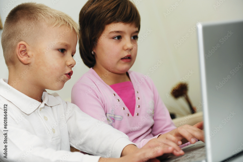 two happy children playing games and learnig education lessons on laptop computer at home two happy children playing games and learnig education lessons on laptop computer at home