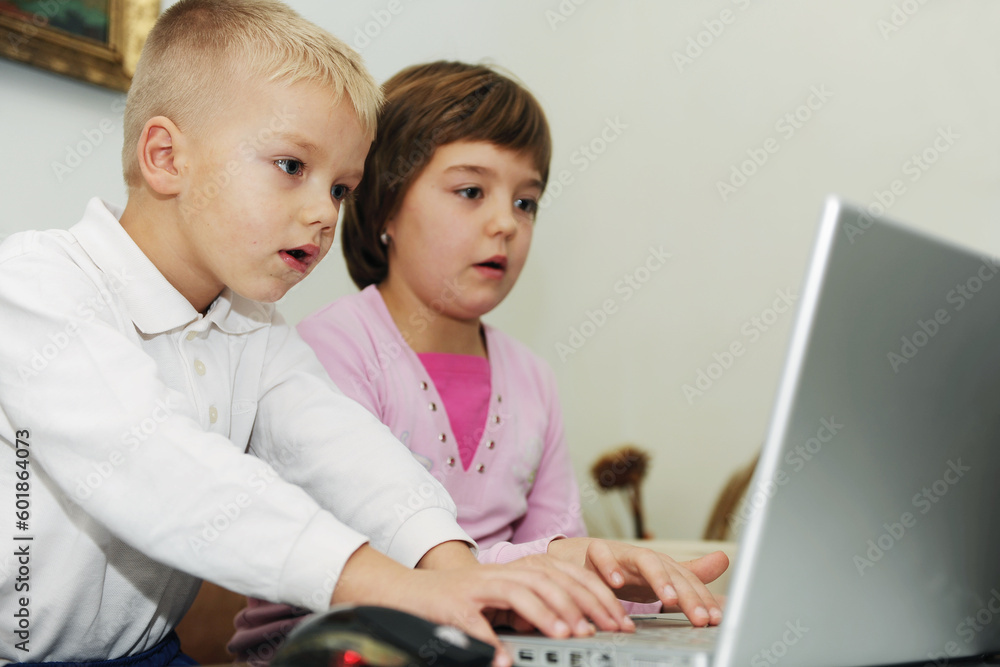 two happy children playing games and learnig education lessons on laptop computer at home two happy children playing games and learnig education lessons on laptop computer at home