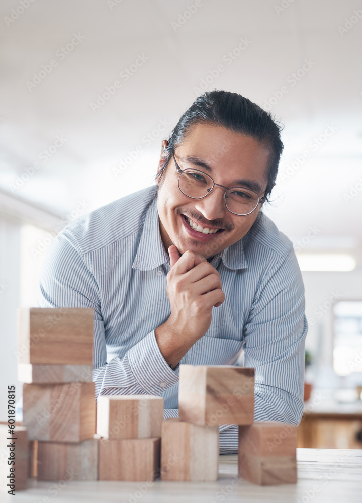 Portrait of businessman with smile, growth and blocks, thinking challenge game and design balance. Engineering, architecture and happiness, asian designer with building block problem solving games.