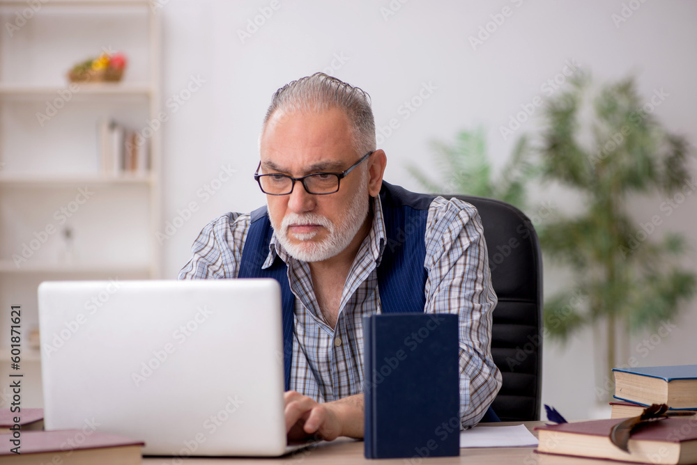 Old male writer sitting at workplace