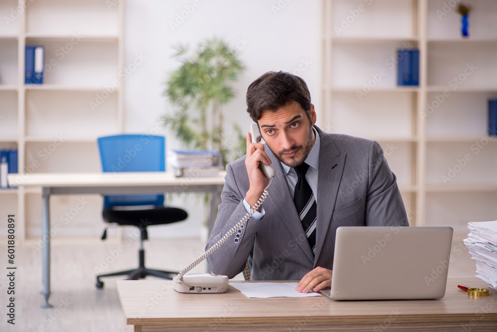 Young male employee and too much work in the office Young male employee and too much work in the office